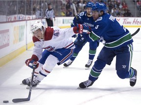 Vancouver Canucks defenceman Derrick Pouliot (5) fights for control of the puck with Montreal Canadiens left wing Daniel Carr (43) during first period NHL action in Vancouver, Tuesday, Dec. 19, 2017.