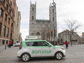 A taxi with Bonjour on the side drives past the Notre-Dame Basilica in Montreal.