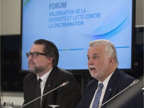 Quebec Premier Philippe Couillard addresses a forum on diversity and anti-discrimination on Tuesday in Quebec City. Quebec Immigration, Diversity and Inclusiveness Minister David Heurtel, left, looks on.