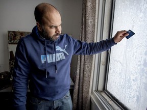 Abdul Waheed Ahmed uses a bank card to scrape ice off the window in the bedroom of his Park Extension apartment.
