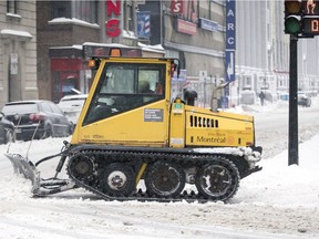 A sidewalk plow heads east on Ste-Catherine St. at Metcalfe on Monday.