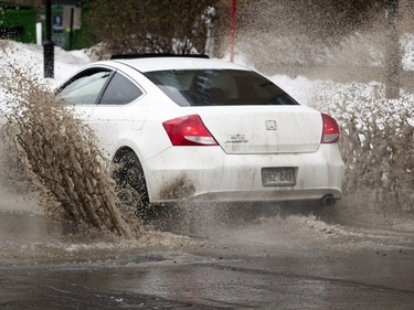 A car splashes through a large puddle at the corner of Jean-D'entrees and St. Jacques Sts. in Montreal on Thursday, January 11, 2018, as the city goes through a thaw after weeks of below-average temperatures.