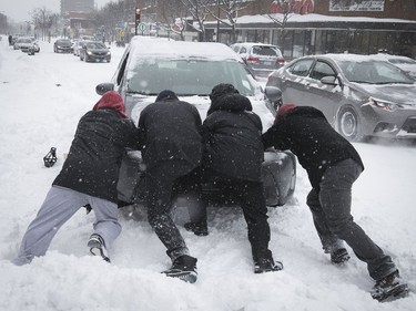 Good Samaritans try to push a car out of a snowbank on Queen Mary Rd. near Circle Rd. on Saturday, Jan. 13, 2018.