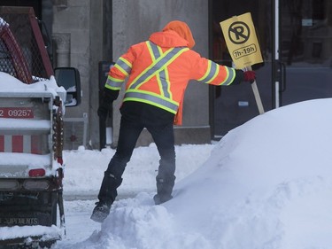 City of Montreal worker puts up snow-clearing signs on Cypress St. on Sunday, Jan. 14, 2018.