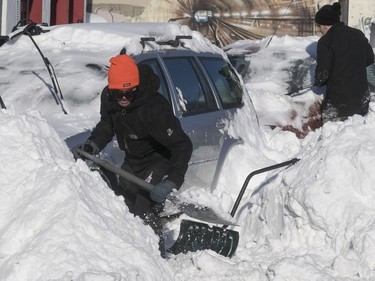 Julian Gammom, front, and Nicholas Hurtubise have a long way to go to free their car from the snowbank on de Maisonneuve Blvd. near Girouard Ave. on Sunday January 14, 2018