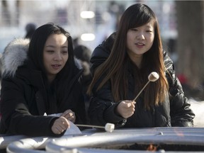 Summer Xia, left, and Susie Wang toast marshmallows over an open fire during the 2017 Fete des Neiges in Montreal.