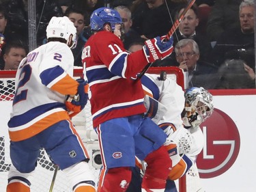 Montreal Canadiens Brendan Gallagher is checked from behind by N.Y. Islanders Nick Leddy as goalie Thomas Greiss makes a save during second period of National Hockey League game in Montreal Monday Jan. 15, 2018.