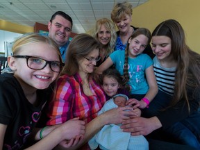 Newborn Caitlyn Stewart is surrounded by dad Dale, mom Ann, holding baby, grandma Judith Giles, wearing purple, midwife Marie Brunet, centre back, and sisters, left to right, Jessica, Vanessa, Kiera and Aimée.