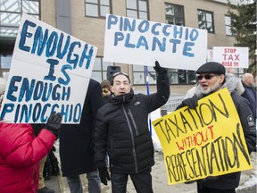 People hold up signs during a rally outside Pointe-Claire city hall on Sunday, protesting against the fallout of the Plante budget on demerged Montreal suburbs.