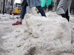 Pedestrians navigate around blocks of ice as Montreal city crews use heavy equipment to break up thick ice in Montreal on Monday, Jan. 29, 2018.