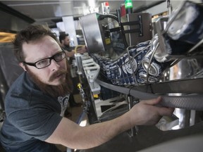 Martin Brooks (front) and Frederic L'Ecuyer pay full attention at the canning process of their Krakhan double IPA beer, at their microbrewery Brasserie Bois Blanc in Hudson.