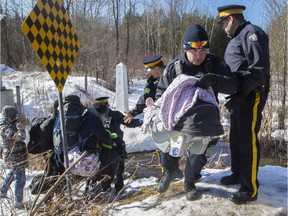 RCMP officers help a group of asylum seekers cross a ditch at the Roxham Rd. "irregular unofficial crossing."