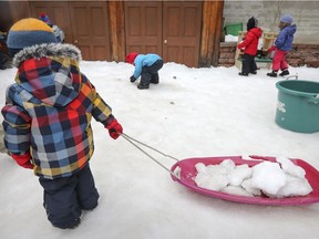 A boy pulls a sled filled with snow as children play outside at a CPE daycare in downtown Montreal Tuesday, February 21, 2017.