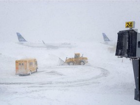 Snow plows move snow as a JetBlue airplane waits outside terminal five at John F. Kennedy International Airport on January 4, 2018 in the Queens borough of New York City. A winter storm is traveling up the east coast of the United States dumping snow and creating blizzard like conditions in many areas.