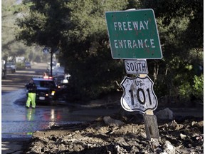 A mud-covered sign over the closed Highway 101 is seen at an overpass Saturday, Jan. 13, 2018, in Montecito, Calif.