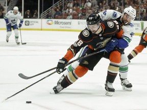 Former Anaheim Ducks centre Logan Shaw protects the puck against the Vancouver Canucks' Sam Gagner in Anaheim, Calif., on Nov. 9, 2017.