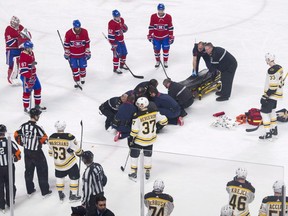 Players from the Montreal Canadiens and Boston Bruins look on as Canadiens' Phillip Danault tended to by paramedics after he was hit in the head by a puck on a shot by Bruins' Zdeno Chara (33) during second period NHL hockey action in Montreal, Saturday, January 13, 2018.