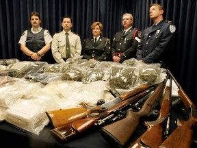Police officers from the RCMP, Sûreté de Québec, Ontario Provincial Police, Timmins Police and the Montreal Police stand behind a table loaded with money, drugs and weapons confiscated during raids that dismantled a drug-smuggling operation headed by Raymond Desfossés during a press conference in September 2004.