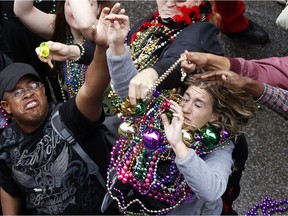 Revelers grab for beads as they are tossed from the balcony of the Royal Sonesta Hotel on Bourbon St. in 2013.