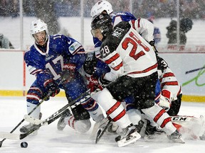 Canada defender Victor Mete and U.S. forward Kailer Yamamoto reach for the puck during the second period of a preliminary round hockey game of the IIHF World Junior Championship in Orchard Park, N.Y., Friday, Dec. 29, 2017. (AP Photo/Adrian Kraus)