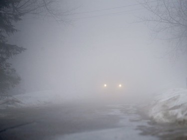 A motorist makes their way down a street during heavy fog in a small town west of Montreal, Friday, January 12, 2018.