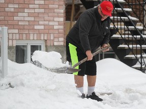 Albert Saccomani shovels his Montreal walkway while wearing his summer attire of sneakers and shorts, Jan. 23, 2018.