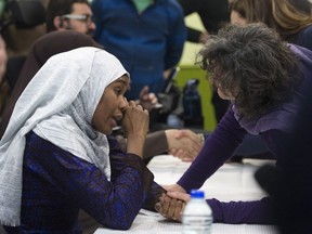 Idiatou Barry, left, wipes her eyes as she speaks with a woman during a gathering at the Centre Islamique de Quebec, marking the first anniversary of the mosque shooting, Saturday, Jan. 27, 2018, in Quebec City. Barry lost her husband, Mamadou Tanou Barry, in the shooting,