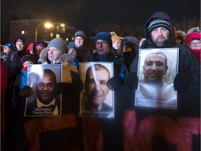 People hold pictures of the victims at a vigil to commemorate the one-year anniversary of the Quebec City mosque shooting, in Quebec City, Monday, Jan. 29, 2018.