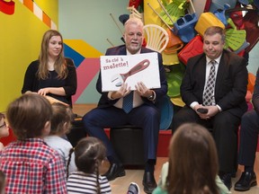 Quebec Premier Philippe Couillard, centre, reads to young children, with Quebec Education and Family Minister Sebastien Proulx and Cassandra Gignac, at the Quebec Museum of Arts in Quebec City on Tuesday.