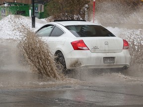 A car splashes through a large puddle at the corner of St. Jacques and Jean-D'Estrees Sts. in Montreal Jan. 11, 2018.