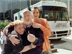 Dans la rue unveils a new Winnebago purchased thanks to a $100,000 donation from Canadian Pacific. Two 'regular' young people are hugging Father Emmett "Pops" Johns, Puce, 20, and Jonathan Lapierre, 16, at Windsor Station in Montreal on April 15, 1998.