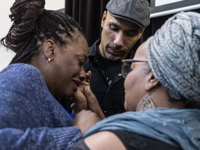 Johanne Coriolan, left, is comforted by Will Prosper and Maguy Metellus as the family announced they are suing the city of Montreal for $150,000, claiming police used excessive force in the death of her father, Pierre Coriolan. (Dave Sidaway / MONTREAL GAZETTE) 
MONTREAL, QUE.: FEBRUARY 7, 2018 -- The family of Pierre Coriolan announced they are suing the city for $150,000, claiming police used excessive force. The media was shown a video of Pierre Coriolan being shot by Montreal police last June. His daughter, Johanne Coriolan, in braids, struggled to compose herself throughout the press conference. in Montreal on Wednesday February 7, 2018. (Dave Sidaway / MONTREAL GAZETTE) ORG XMIT: 60157