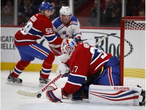 Montreal Canadiens goaltender Antti Niemi pulls in the puck to cover up as Montreal Canadiens' Noah Juulsen and New York Rangers' J.T. Miller look on in Montreal on Feb. 22, 2018.
