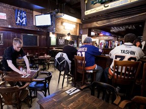 Adam Ramsey prepares tables as a few hockey fans sit at the bar in McLean's Pub on Wednesday, Feb. 28, 2018.