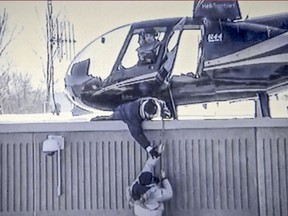 An accomplice tries to help Benjamin Hudon-Barbeau to a helicopter on the roof of the the St-Jérôme detention centre during his escape with fellow inmate Dany Provencal on March 17 2013.