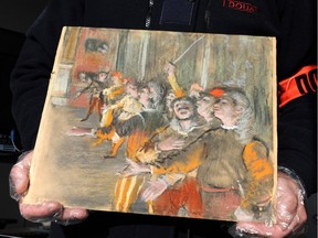 This handout photo shows a French custom officer holding a Degas painting stolen from a museum in Marseille nine years ago has been found on a bus near Paris, the French Culture Minister said on February 23.