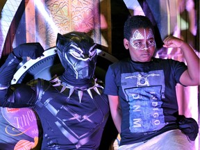 A fan poses with a cosplayer portraying a character from the 2018 US superhero film based on the Marvel Comics character, 'The Black Panther' pose in the Kenyan capital, Nairobi on February 14, 2018. Kenya's Hollywood sensation Lupita Nyong'o appears in the popular Marvel comics adaption of the Black Panther playing the character of 'Nakia'.
