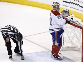 Linesman Shane Heyer (55) picks up the puck after Montreal Canadiens goaltender Carey Price (31) allowed a goal to Arizona Coyotes' Josh Archibald Feb. 15, 2018, in Glendale, Ariz. The Coyotes defeated the Canadiens 5-2.