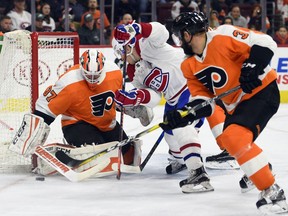Philadelphia Flyers goalie Brian Elliott, left, makes a save on a shot by Montreal Canadiens' Brendan Gallagher, center, as Radko Gudas defends during the first period of an NHL hockey game Thursday, Feb. 8, 2018, in Philadelphia.