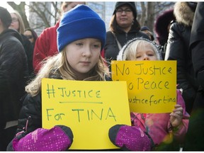 Two young girls hold up signs during a rally in memory of Tina Fontaine in Montreal on Saturday, Feb. 24, 2018.