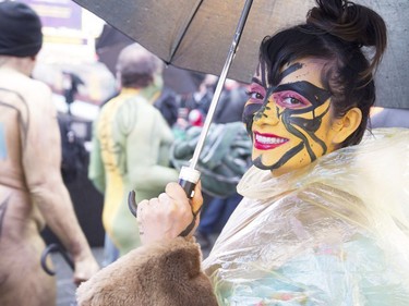 A nude model in a see-through poncho poses with her umbrella in the rain and cold during the Polar Bear Paint body-painting event in New York City's Times Square Feb. 10, 2018.