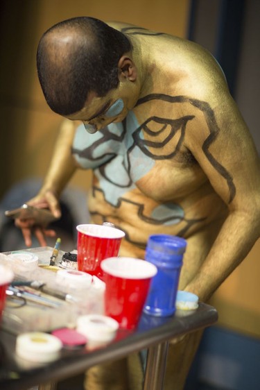 This photo provided by Andy Golub shows a  nude model getting ready to take part in the Polar Bear Paint body-painting event in the rain and cold of New York City's Times Square ponders what color to apply next on Saturday Feb. 10, 2018. (Andy Golub  via AP) ORG XMIT: NYSH205