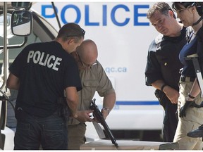 Montreal police officers look at a weapon seized from a house in Montreal in 2013.