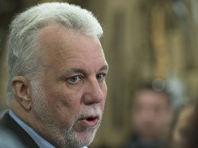 Quebec Premier Philippe Couillard responds to reporters' questions during a visit to a furniture store warehouse in Quebec City on Wednesday, Feb. 28, 2018.