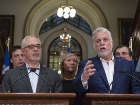 Quebec Premier Philippe Couillard speaks during a news conference marking the end of a pre-session government caucus meeting, Thursday, February 1, 2018 at the legislature in Quebec City. Quebec Finance Minister Carlos Leitao, left, looks on.