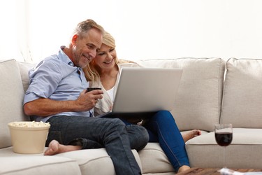 Portrait of happy mature couple on couch using a laptop while at home