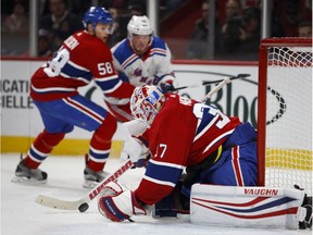 Montreal Canadiens goaltender Antti Niemi pulls in the puck to cover up as Montreal teammate Noah Juulsen and New York Rangers' J.T. Miller look on during in Montreal on Feb. 22, 2018.
