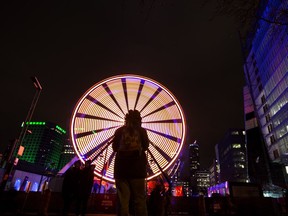 A woman takes a photo of the Ferris Wheel in the Quarter des spectacles, part of Nuit Blanche activities and Montreal en Lumière in Montreal, March 3, 2018.