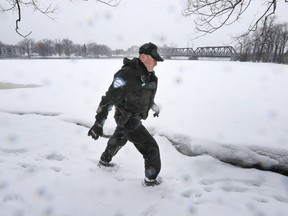 Montreal police officer searches along the bank of the Rivière des Prairies for missing 10-year-old Ariel Jeffrey Kouakou Tuesday March 13, 2018.