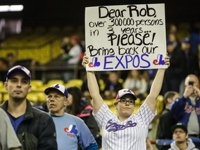 A baseball fan holds a sign asking to bring back the Montreal Expos before the second exhibition game between the Toronto Blue Jays and the Boston Red Sox at the Olympic Stadium in Montreal on Saturday, April 2, 2016.